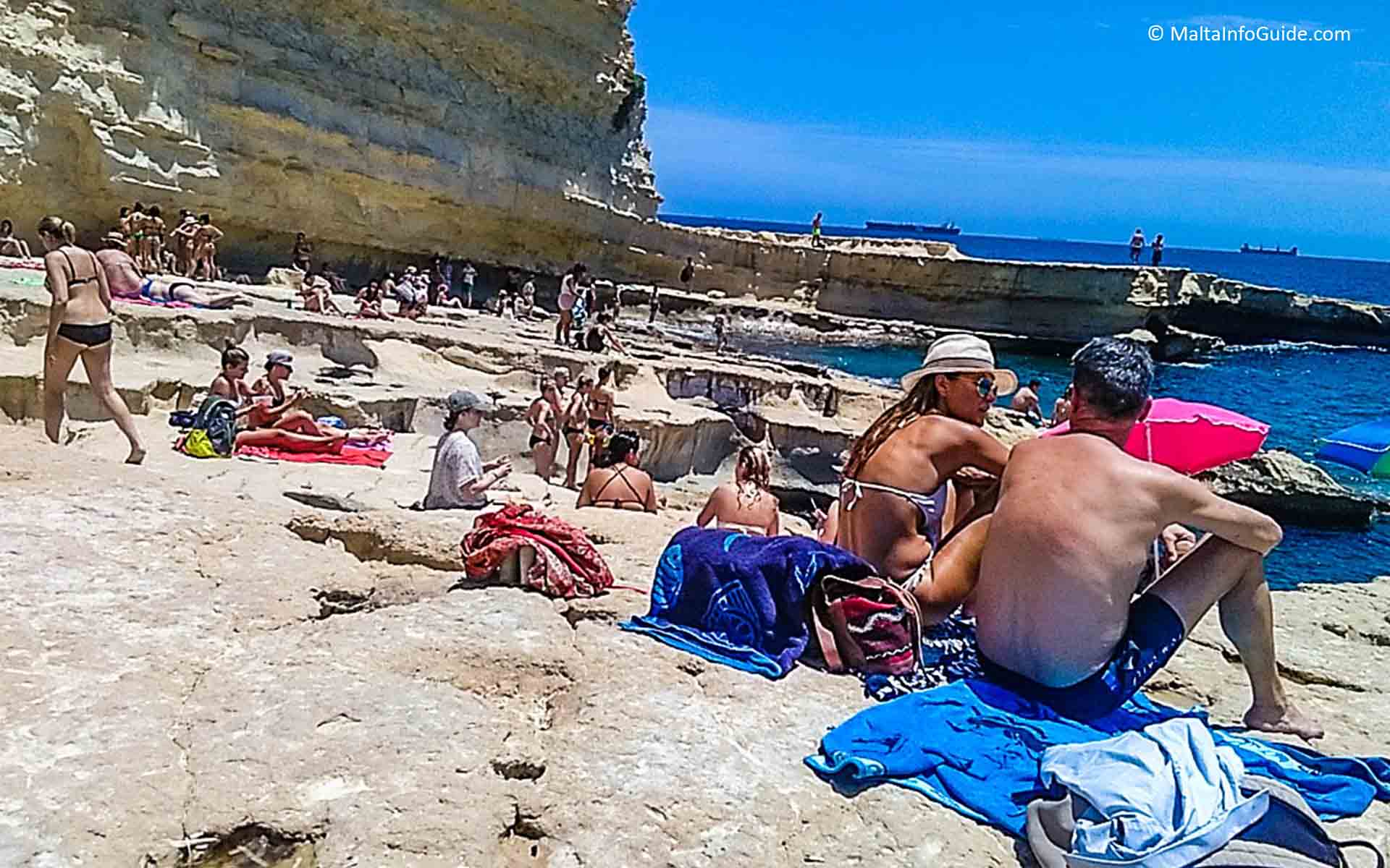 People sitting on the rocks at St. Peter's Pool Malta