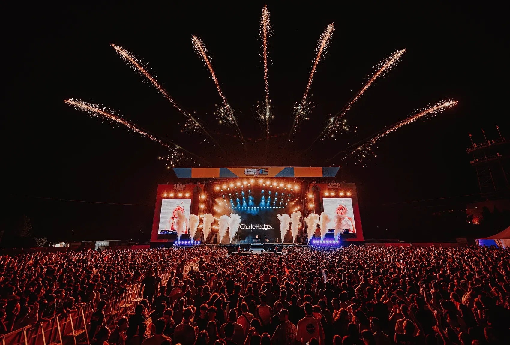 Crowd at a Summer Daze Malta concert with fireworks above the stage.