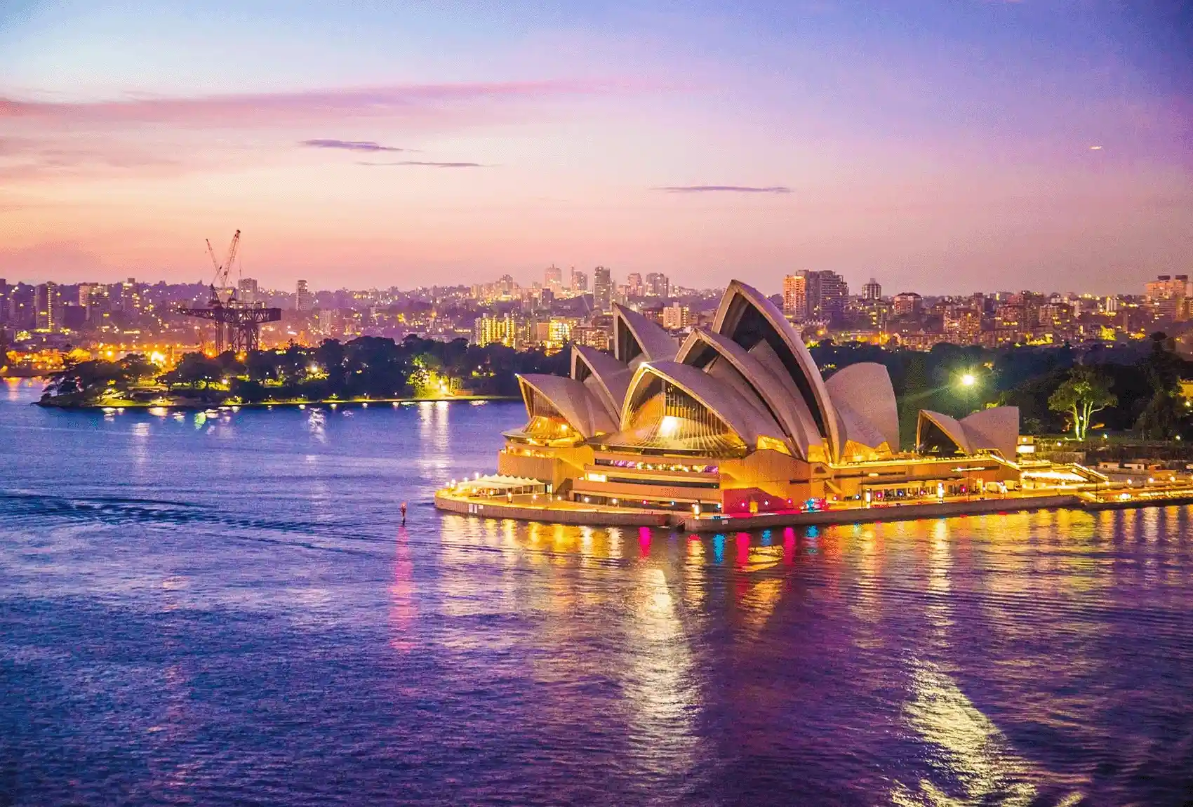 Sydney Opera House beside the harbour at colourful sunset.
