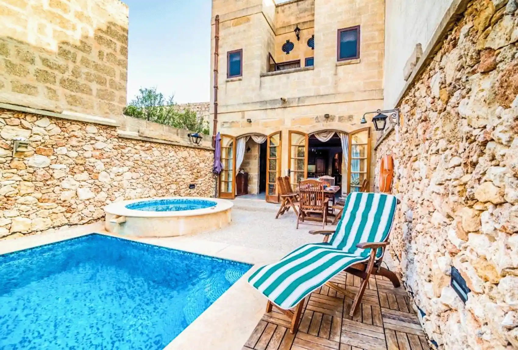 Private pool courtyard with outdoor dining in a traditional limestone setting at Ta’ Manwel Farmhouse, Nadur, Gozo, Malta.