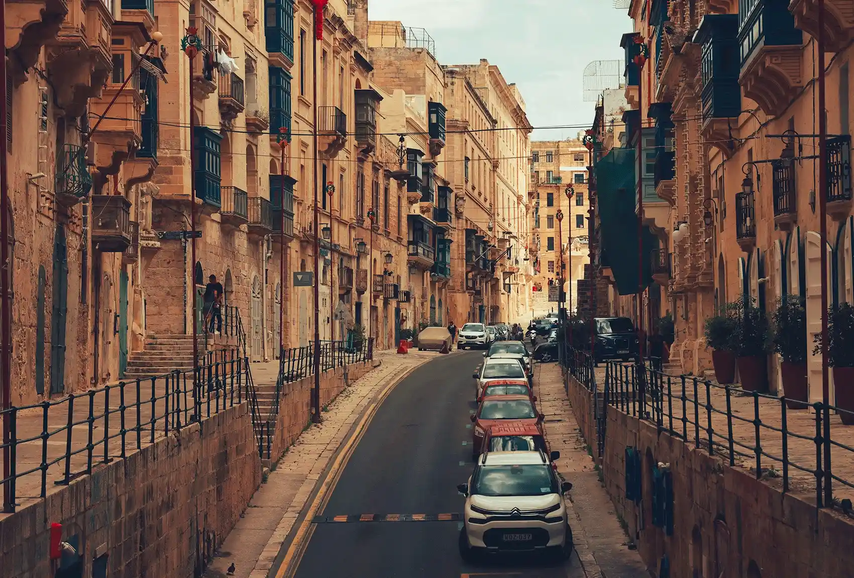 Cars parked closely along a narrow Valletta street.