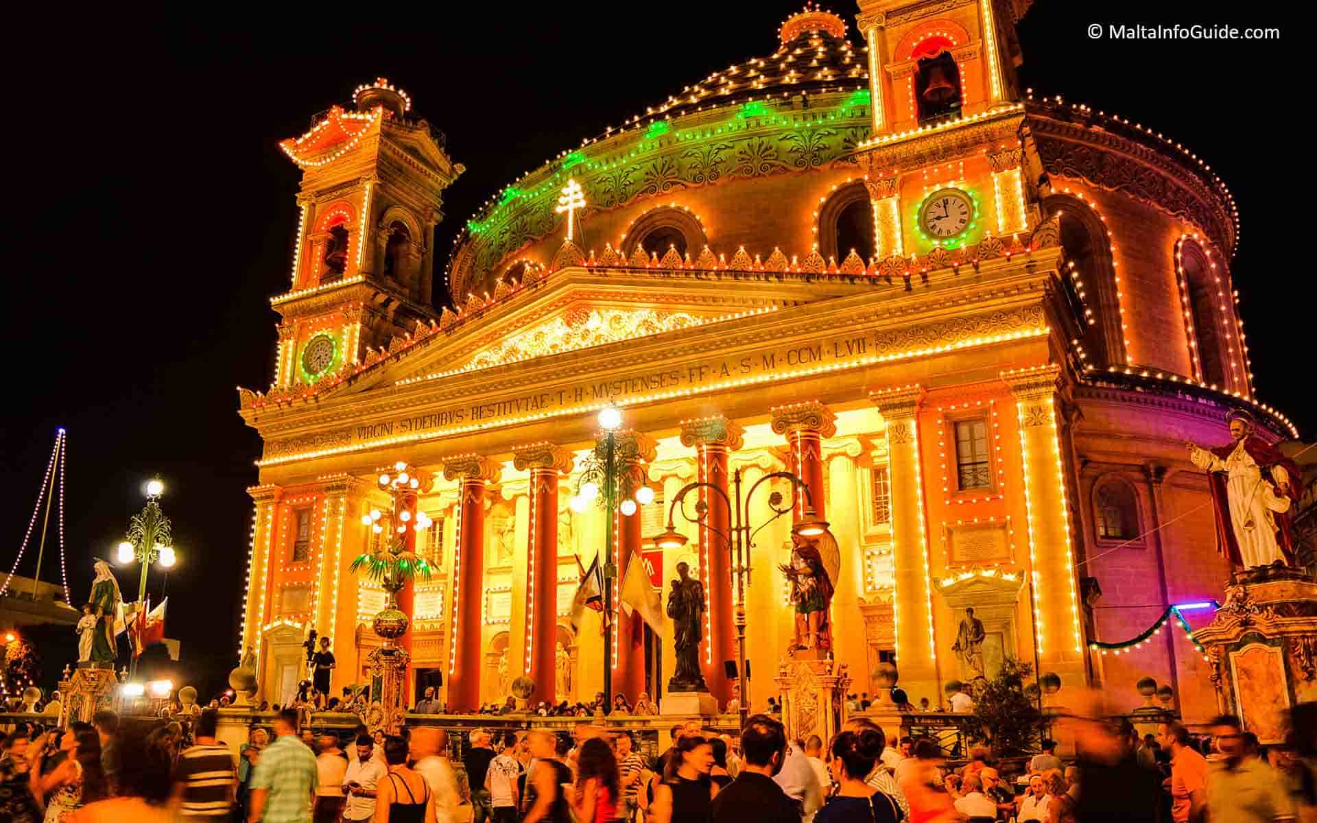 Mosta church facade lit up on the day of the feast.