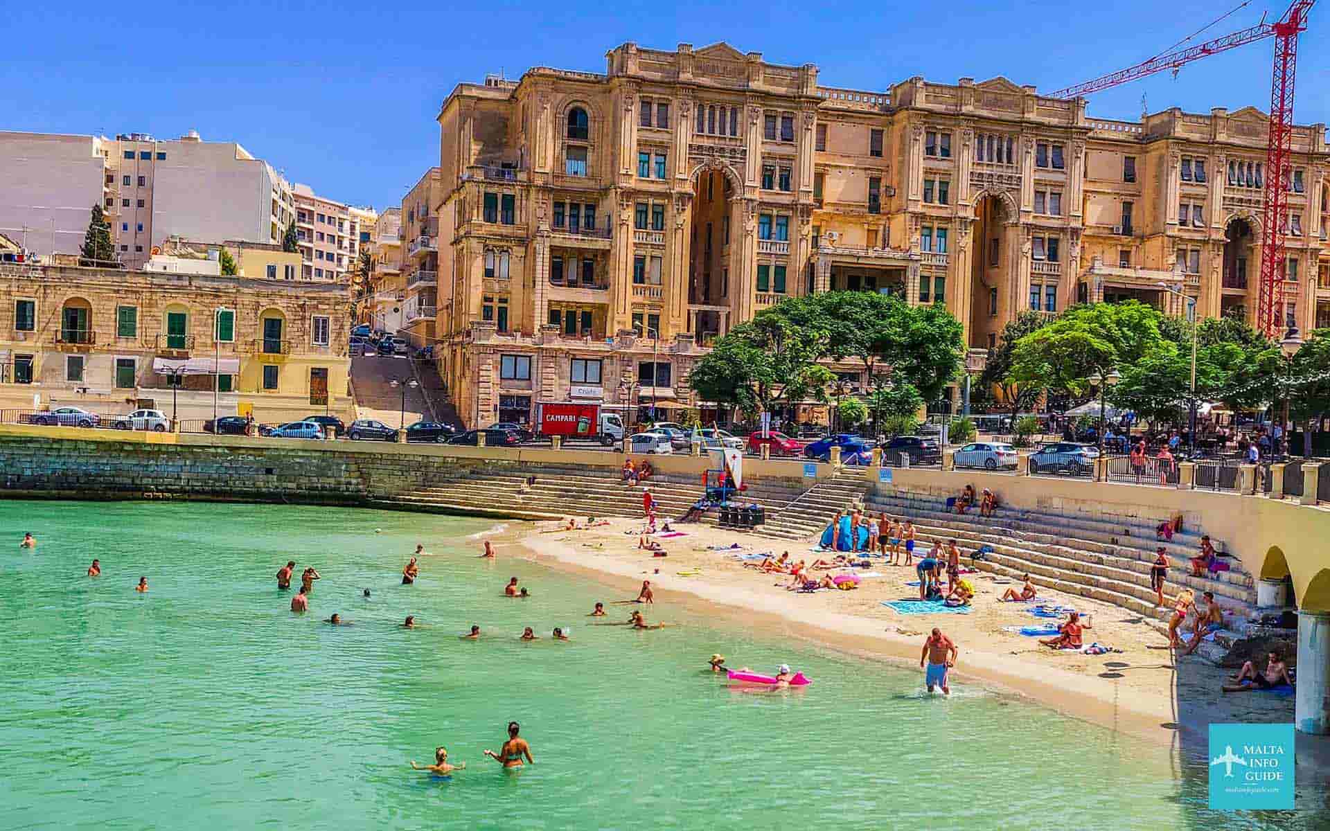 People swimming and sunbathing at Balluta bay beach Malta.