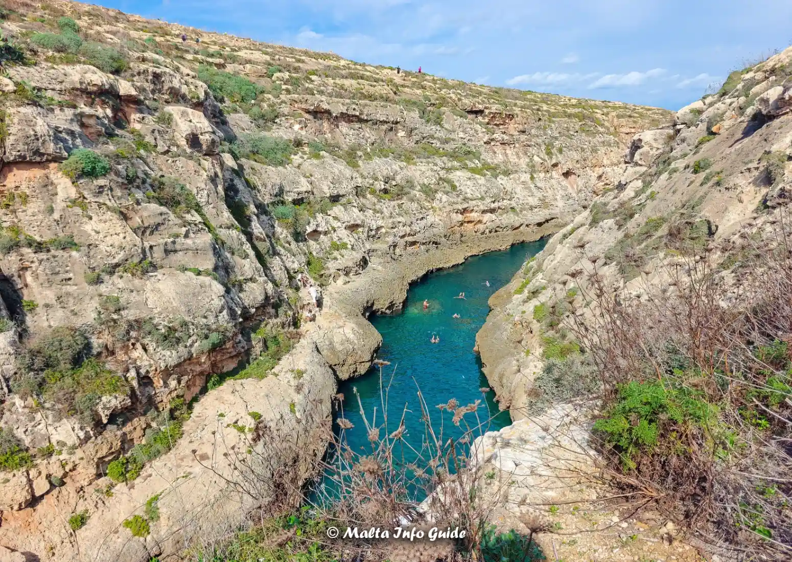 Swimmers explore Wied l-Għasri's narrow turquoise gorge in Gozo.