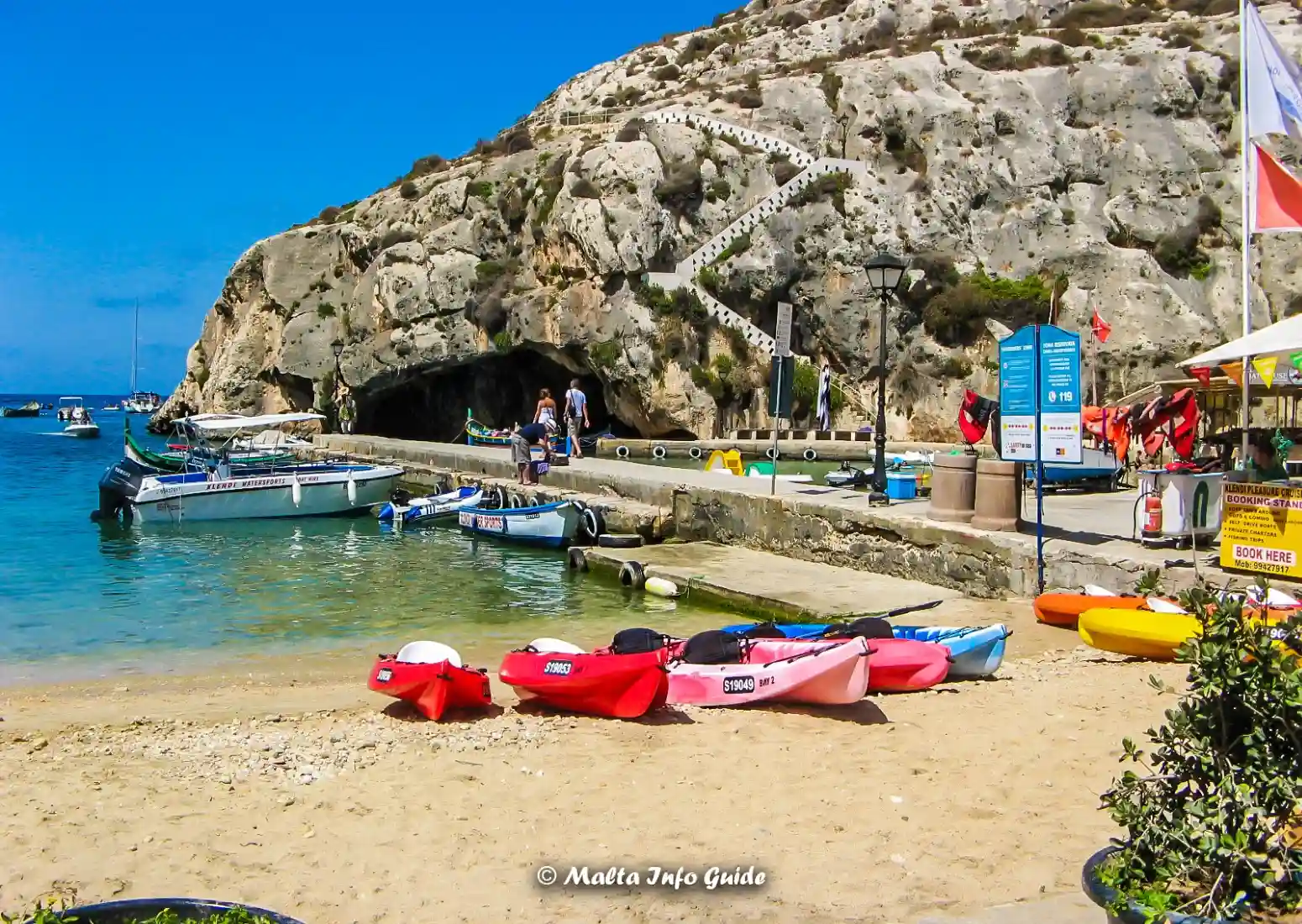 Small beach at Xlendi Bay in Gozo with boats and kayaks.