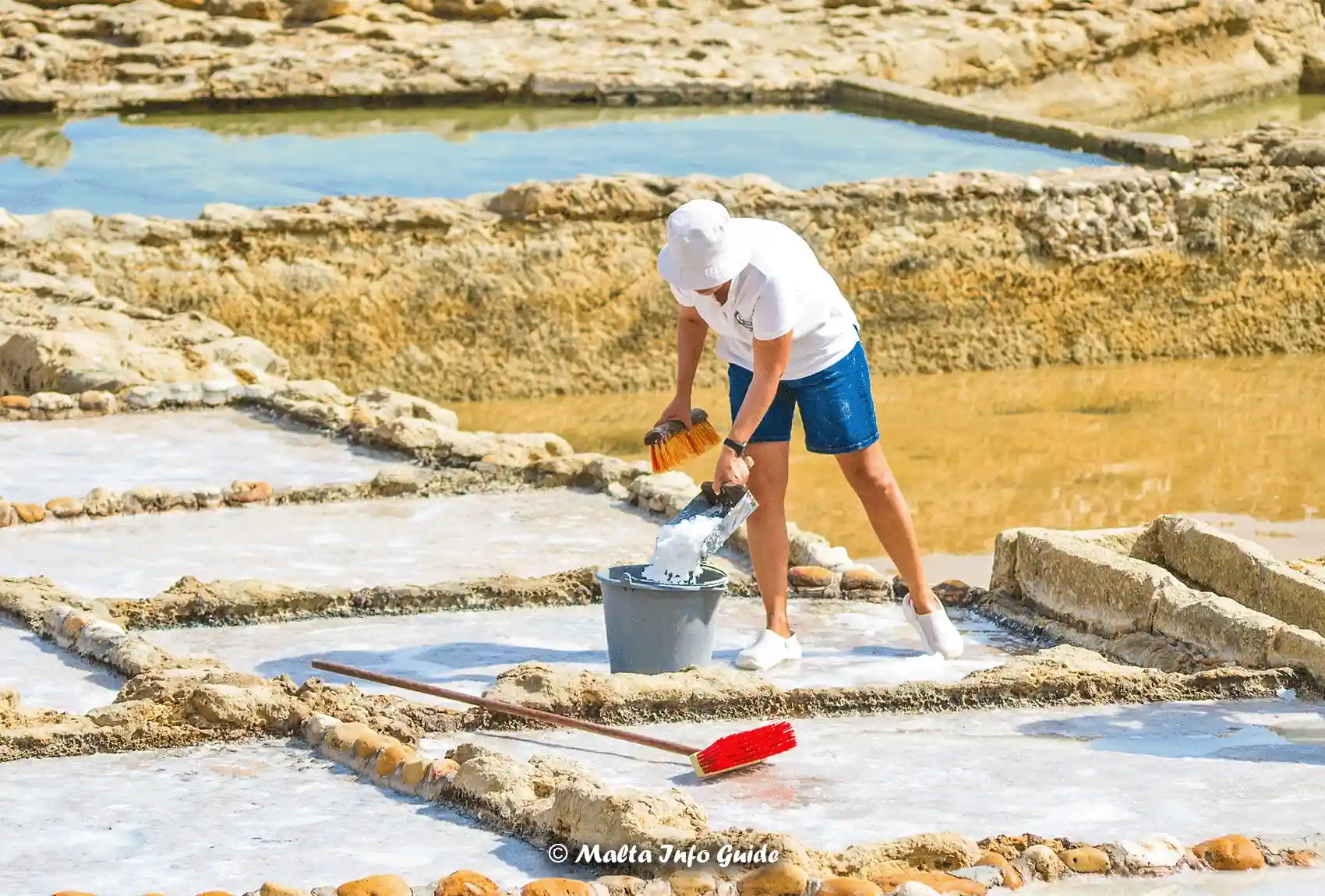 Woman collecting sea salt at Gozo’s famous Xwejni Salt Pans.